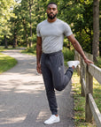 Man warming up beside a park rail wearing MOVE Sport Apparel Men’s Essential Jogger Black Label in Heather Black.