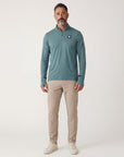 Full-body studio portrait of a man wearing the Heather North Atlantic MOVE Sport Apparel Essential Quarter Zip Pro with sand trousers and off-white sneakers.