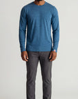 Full-body studio view of a man wearing the MOVE Sport Apparel Men’s Essential Long Sleeve in Blue Mirage with charcoal trousers and white sneakers.