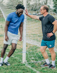 MOVE sport apparel Agility 6 inch training shorts in teal worn by a man standing next to a soccer goal