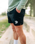 MOVE sport apparel Agility 6 inch black training shorts with white logo detail worn by a man outdoors