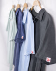 MOVE sport apparel Essential Polo Shirts in various colors hanging on wooden hangers against a white wall.