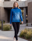 A woman wearing a MOVE sport apparel blue waffle-knit full-zip hoodie with a chest pocket, walking outdoors.