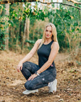 MOVE sport apparel women's black cropped tank top worn by a blonde athlete crouching in a forest setting