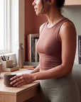 MOVE sport apparel women's mauve cropped tank top in stretchy fabric, worn by a woman standing at a desk.