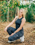Woman wearing MOVE Sport Apparel women’s 25-Inch Running Tights in Black Camouflage during a woodland warm-up.