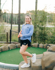 MOVE Sport Apparel women’s Black Label Lightweight Sun Hoodie: Woman wearing Deep Periwinkle sun hoodie beside a miniature golf green.