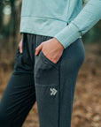 Close-up of a woman wearing dark Essential Joggers outdoors, showing pocket and thigh embellishment.