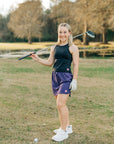 Woman wearing a purple MOVE Sport Apparel women’s Skort on an outdoor golf course.