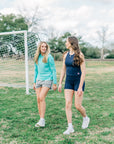 MOVE Sport Apparel women’s Black Label Lightweight Sun Hoodie: Woman wearing Aqua Splash sun hoodie beside a friend on a grass field.
