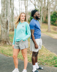 MOVE Sport Apparel women’s Black Label Lightweight Sun Hoodie: Woman wearing Aqua Splash sun hoodie beside a man on a wooded path, side view.