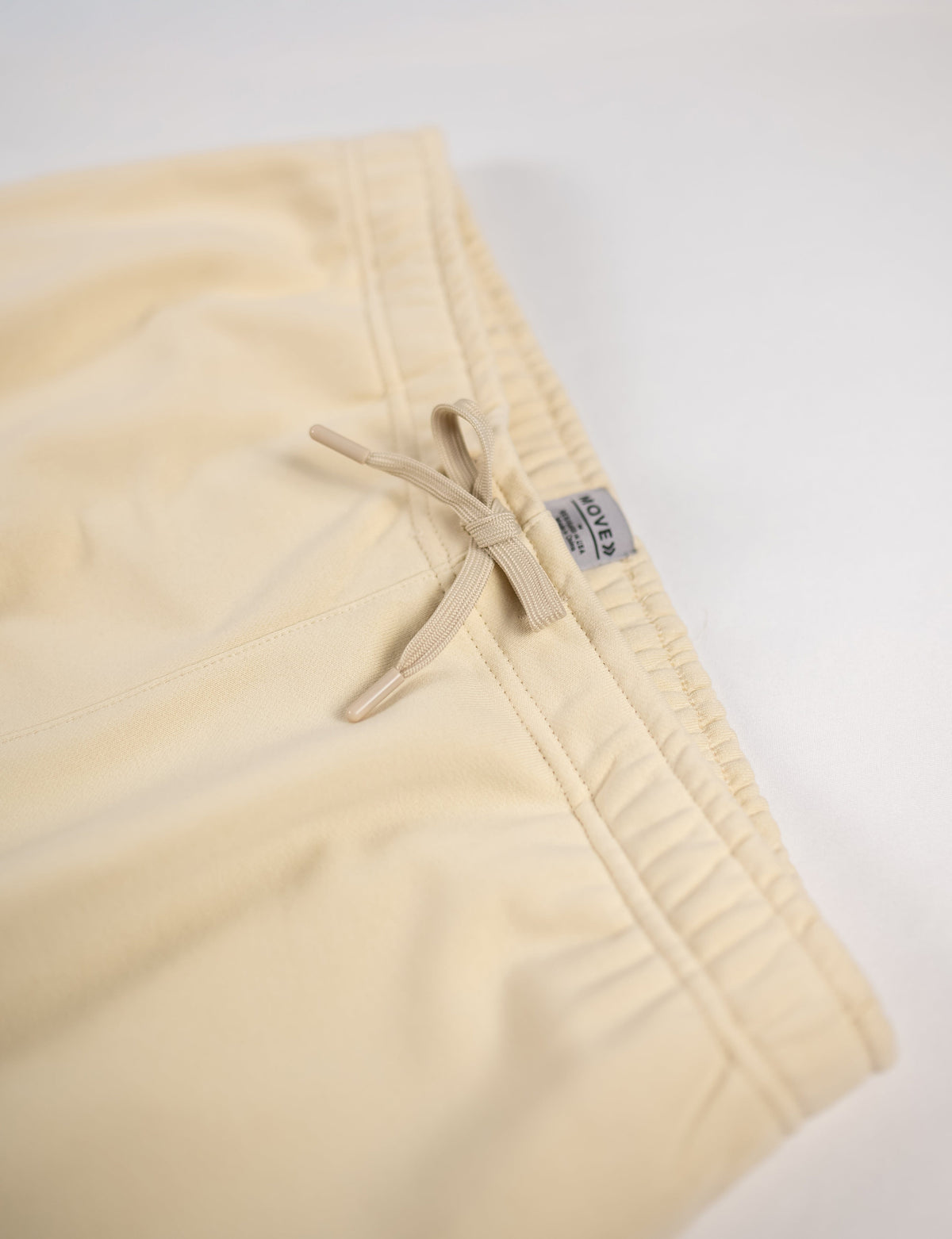 Close view of the drawstring waistband and original label on MOVE Sport Apparel French Terry Joggers in Natural.