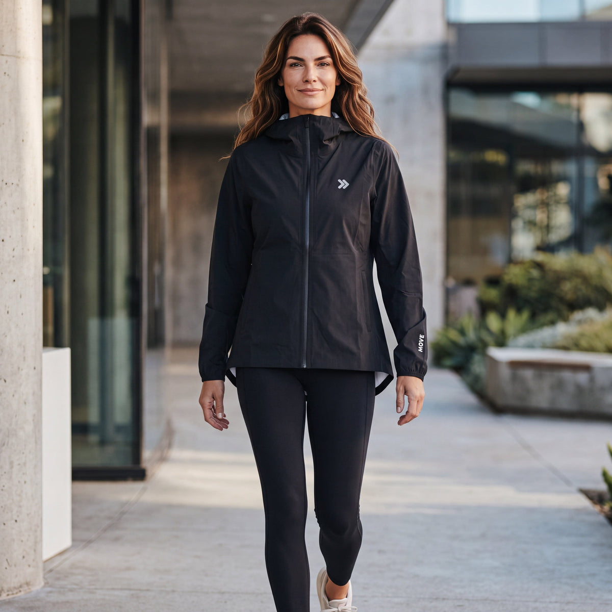 Woman wearing the black MOVE Sport Apparel women’s AquaLight jacket in an urban outdoor setting.
