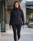 Woman wearing the black MOVE Sport Apparel women’s AquaLight jacket in an urban outdoor setting.