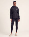 Studio model wearing the black MOVE Sport Apparel women’s AquaLight Packable Jacket with hood and full front zipper.