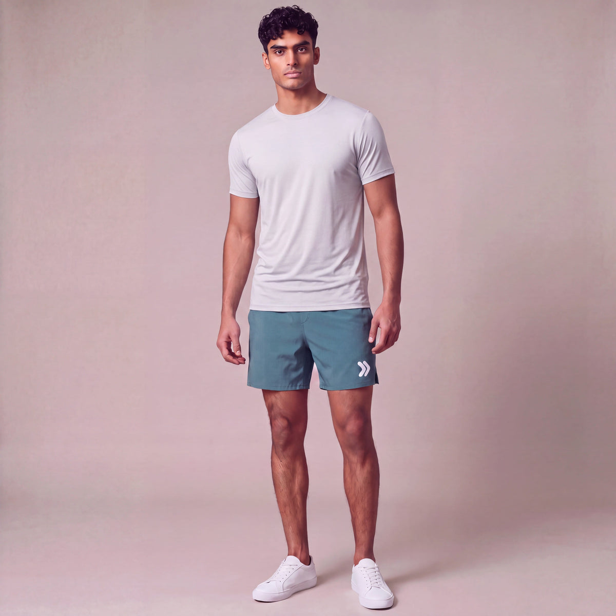 MOVE Sport Apparel Men’s Core Athletic Training Shorts in Deep Sea teal, worn by an adult man with a fitted lightweight athletic tee and white trainers in a neutral studio, showing the rounded white leg embellishment.