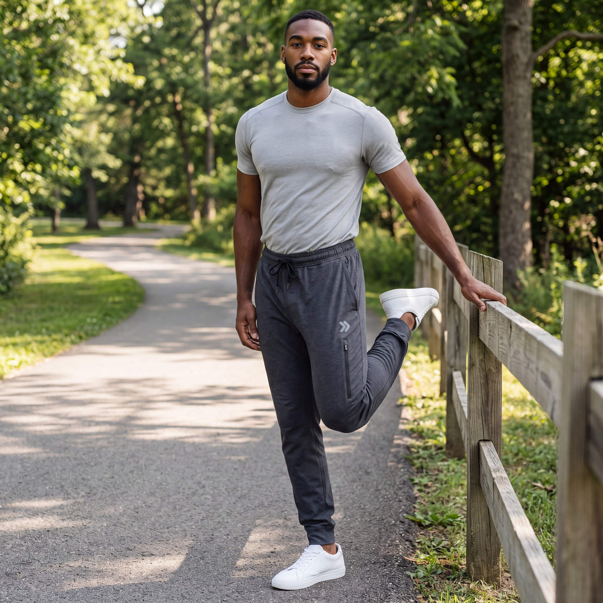Man warming up beside a park rail wearing MOVE Sport Apparel Men’s Essential Jogger Black Label in Heather Black.