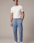 Male model wearing Blue Mirage MOVE Sport Apparel men’s Essential Jogger with a plain off-white T-shirt in a neutral studio.