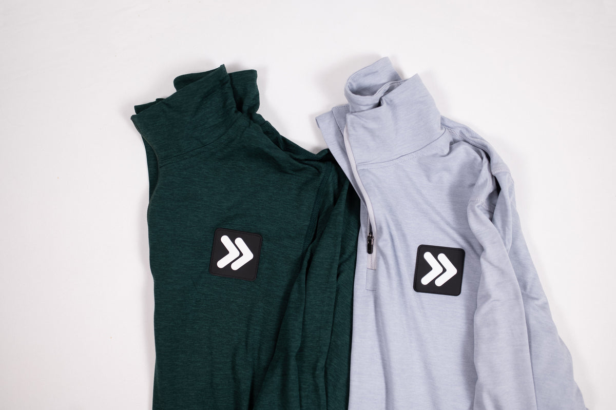 Close view of MOVE Sport Apparel Men’s Essential Quarter Zip in Silver Cloud beside Pine Grove, showing original chest patches.