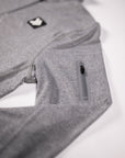 Close view of the Heather Classic Gray Essential Quarter Zip Pro original chest patch, heather fabric and zippered sleeve pocket.