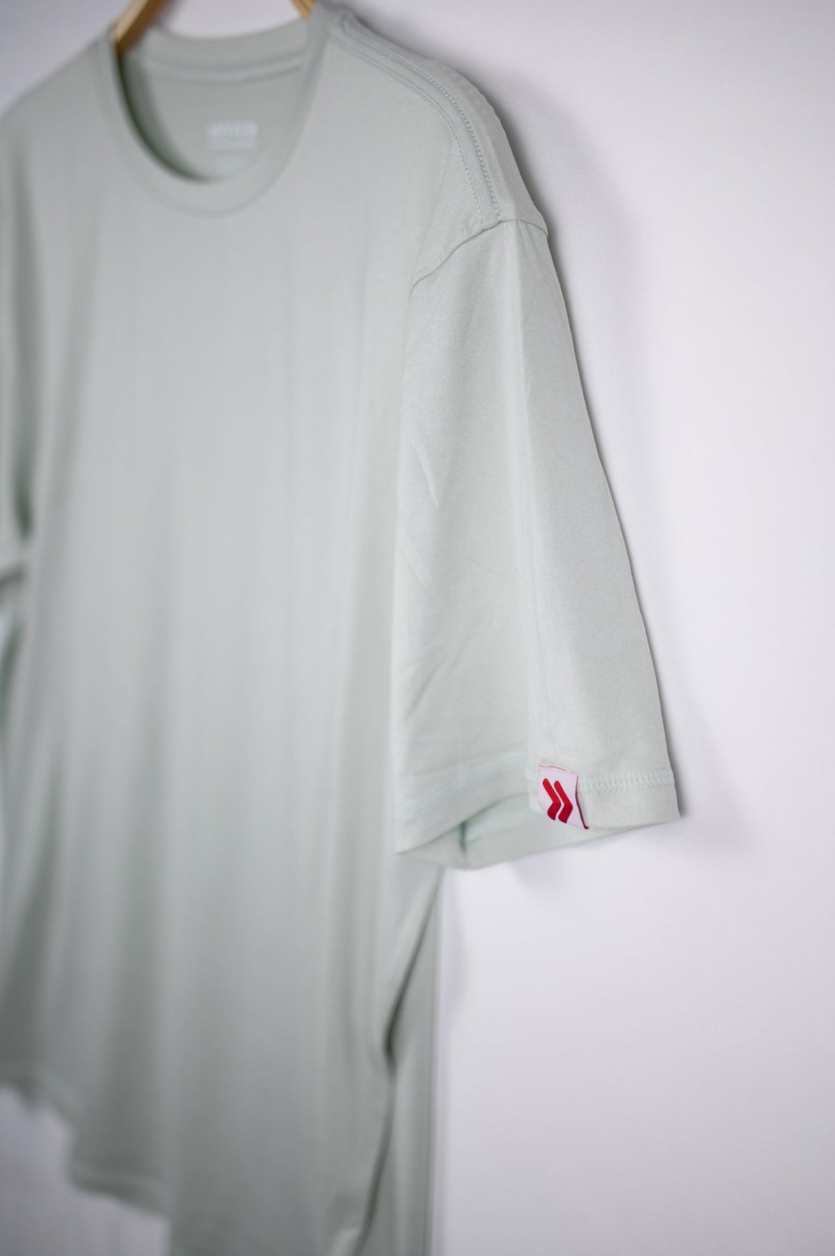 MOVE Sport Apparel men’s Essential Short Sleeve: Heather Aqua Glass shirt showing its original sleeve tab.