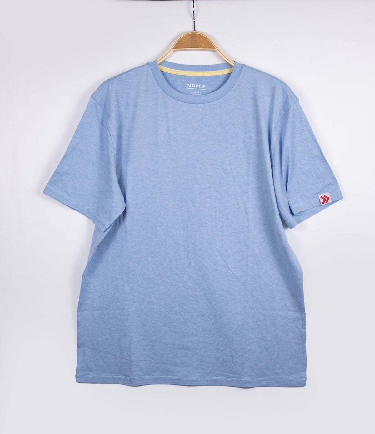 MOVE Sport Apparel men’s Essential Short Sleeve: Heather Chambray Blue shirt hanging against a pale background.