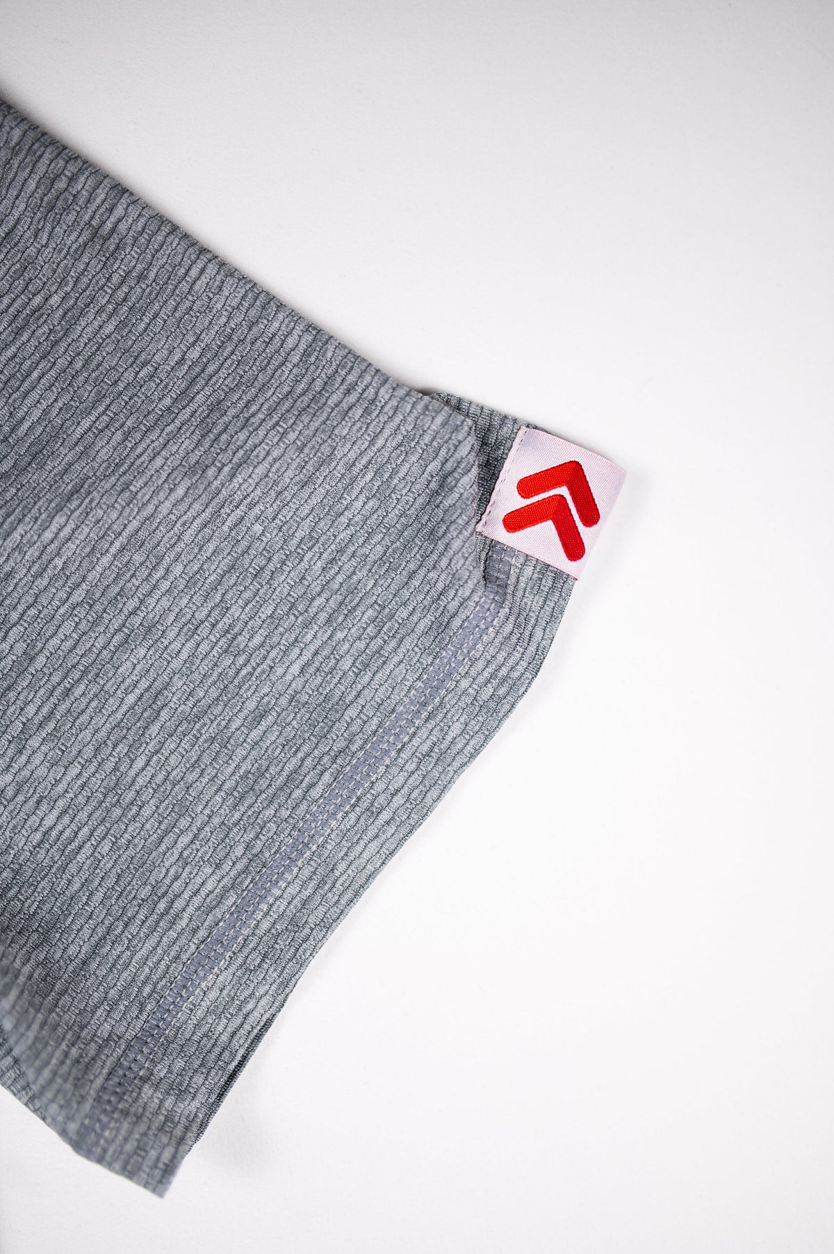 Ultimate Gray LuxDry tee sleeve hem and original white tab with red double chevrons.