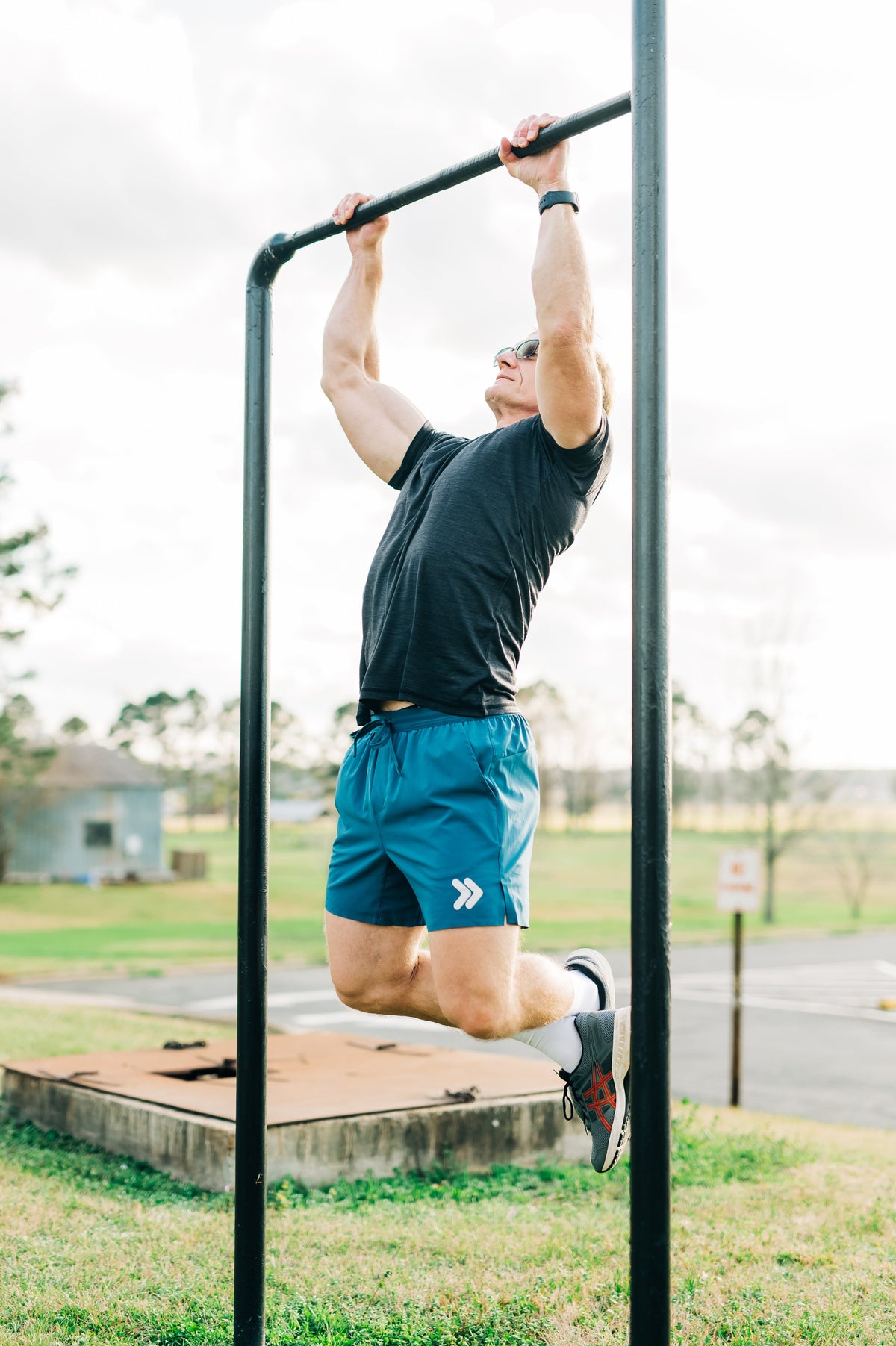 Man wearing a charcoal MOVE Sport Apparel men’s Merino Short Sleeve while performing a pull-up outdoors.