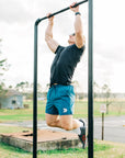 Man wearing a charcoal MOVE Sport Apparel men’s Merino Short Sleeve while performing a pull-up outdoors.