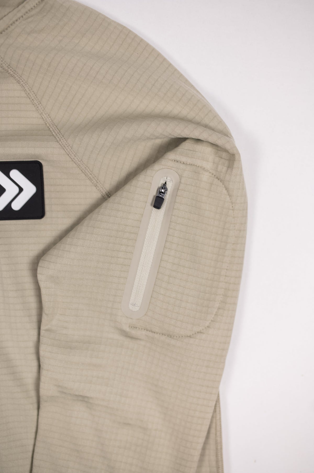 Close view of the Pelican MOVE Sport Apparel waffle quarter zip chest patch and zippered sleeve pocket.