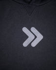 Close-up of the original grey centered double-chevron embellishment on the black MOVE Sport Apparel Logo Hoodie.