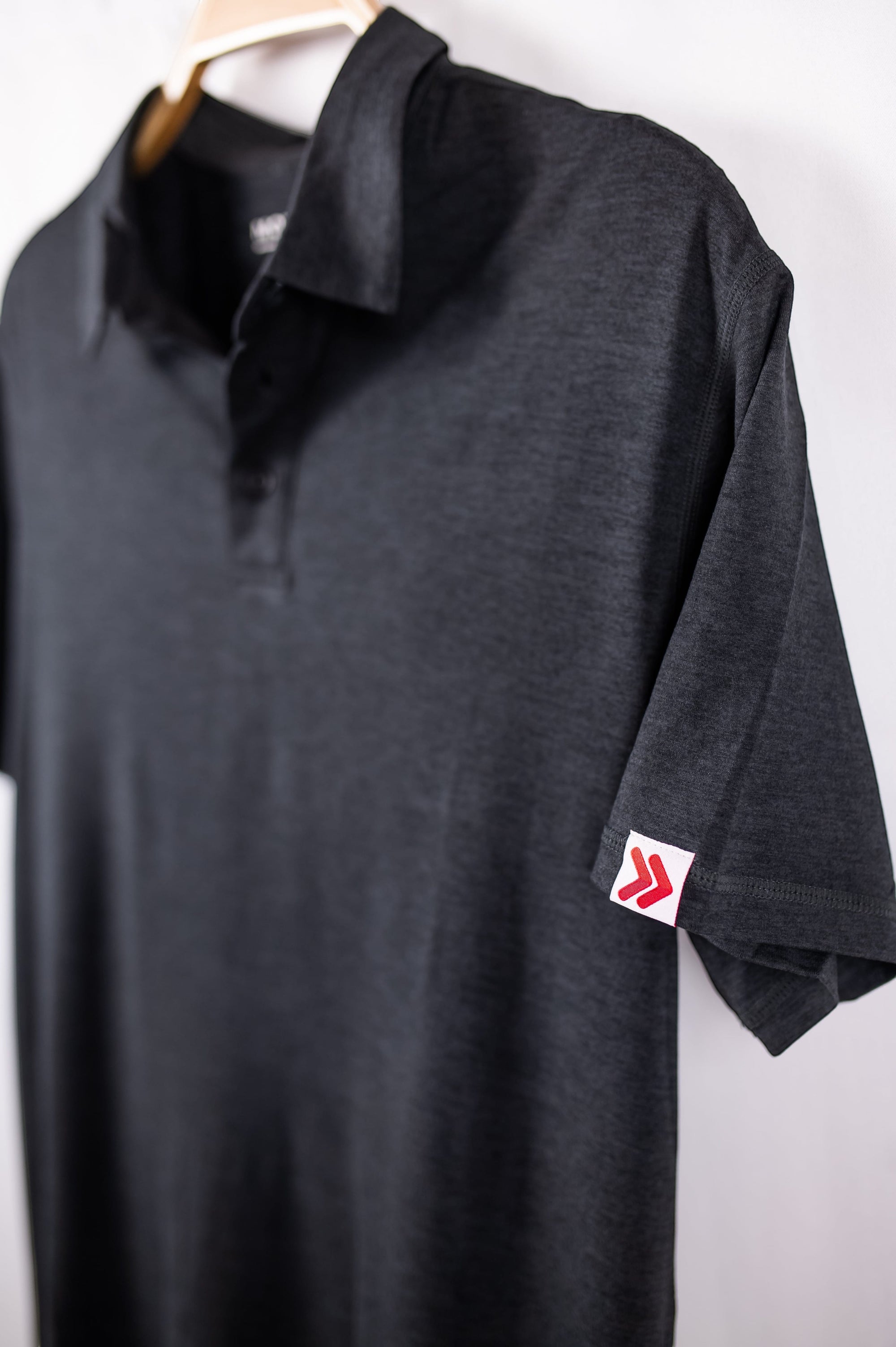 MOVE sport apparel Essential Polo Shirt in charcoal grey moisture-wicking fabric with a small red logo on the sleeve