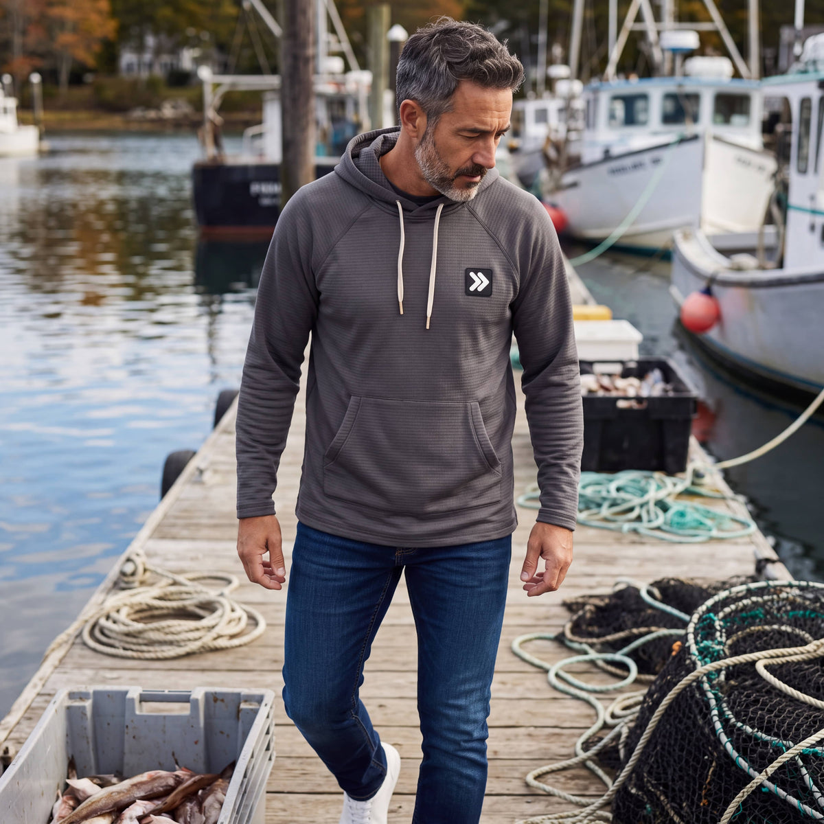 Man wearing a charcoal grey MOVE sport apparel waffle-knit hoodie with raglan sleeves on a wooden boat dock.