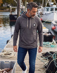 Man wearing a charcoal grey MOVE sport apparel waffle-knit hoodie with raglan sleeves on a wooden boat dock.