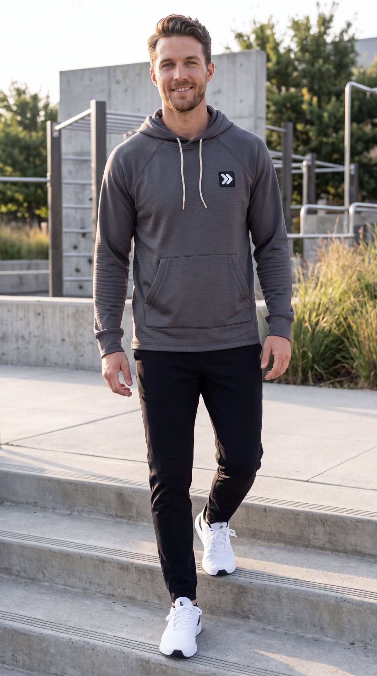 Male model wearing the charcoal MOVE Sport Apparel waffle pullover hoodie while walking on outdoor concrete steps.