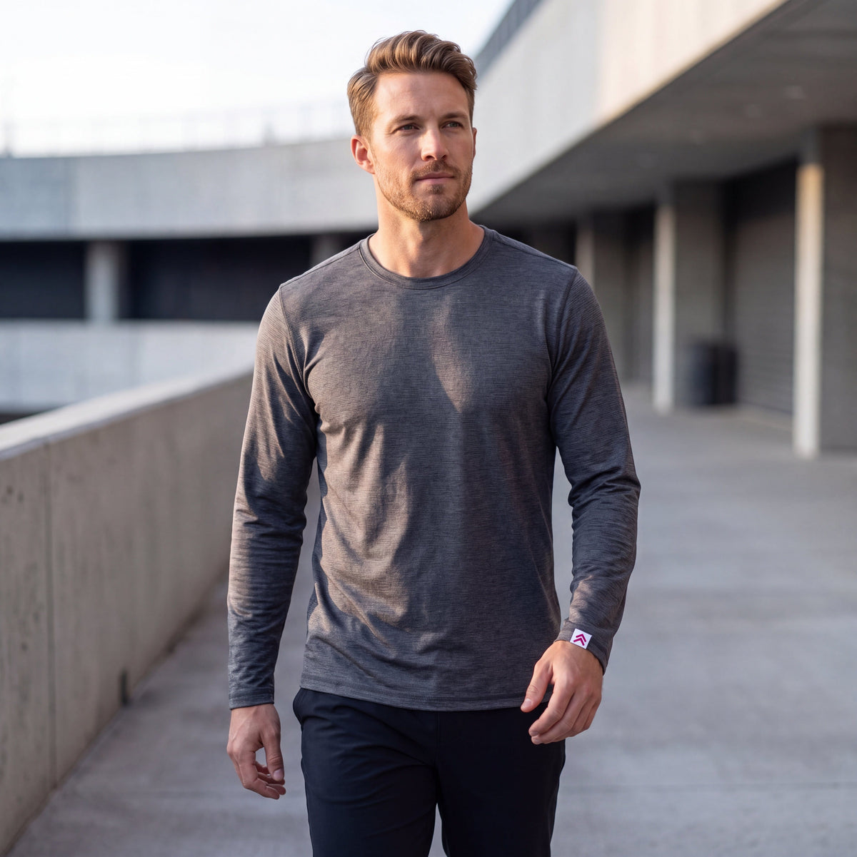 Man wearing MOVE Sport Apparel men’s LuxDry long sleeve in Volcanic glass outside a modern concrete building.