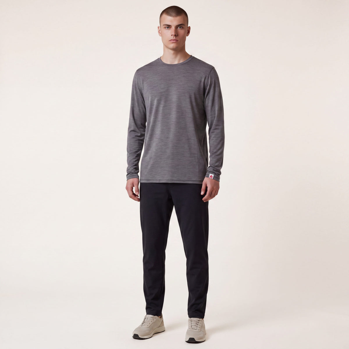Full body neutral studio view of a man wearing MOVE Sport Apparel Men’s Merino Long Sleeve in Granite Gray with dark trousers.