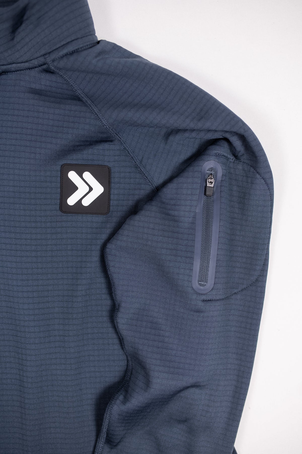 Close view of the India Ink MOVE Sport Apparel waffle quarter zip waffle knit, original chest patch and zippered sleeve pocket.