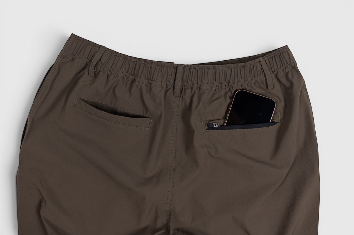 MOVE sport apparel men's brown ripstop joggers featuring a zippered back pocket holding a smartphone