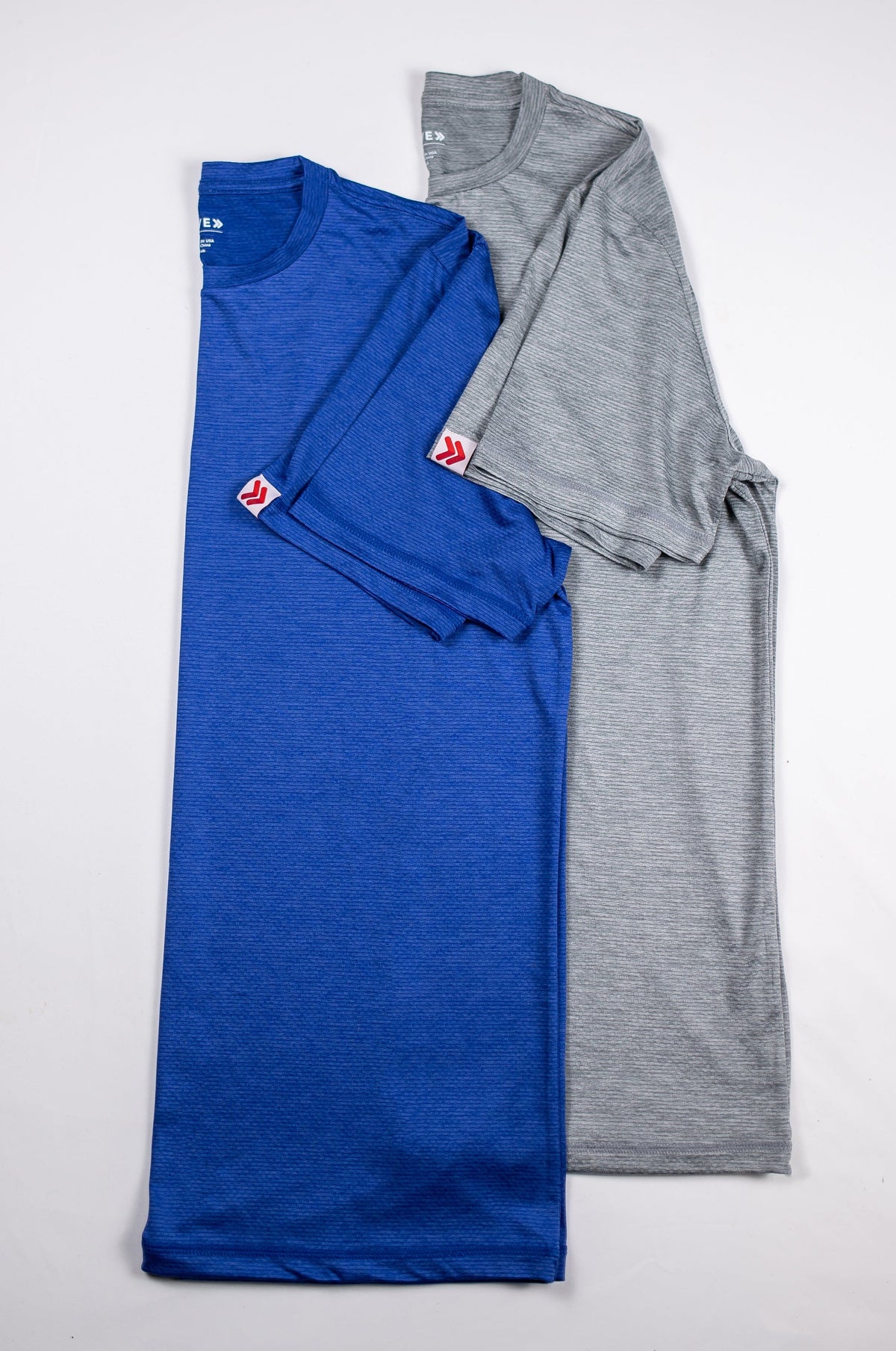 Blue and grey LuxDry Training T-Shirts arranged together as a flat lay.