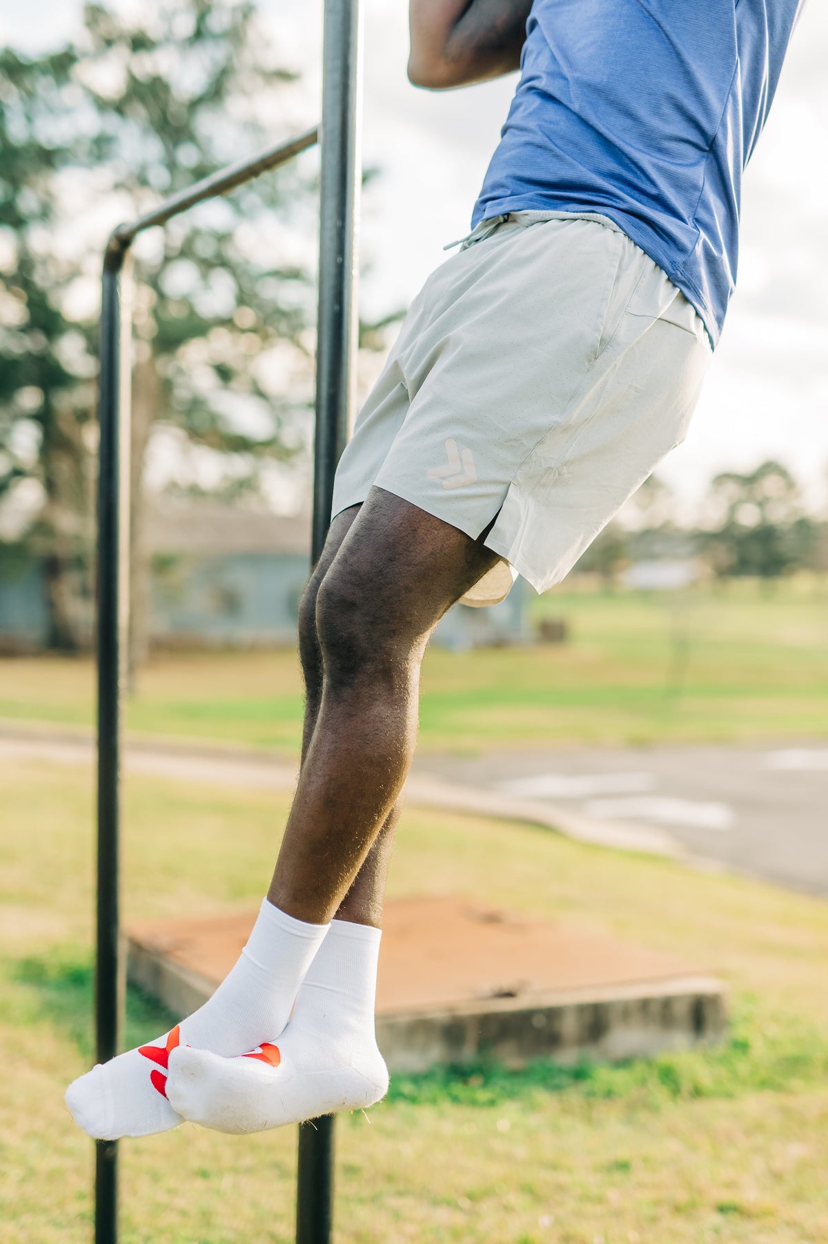 Blue LuxDry tee and light shorts worn during an outdoor pull-up, cropped outfit detail.