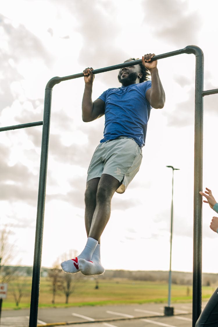 Man wearing the blue MOVE Sport Apparel men’s LuxDry Training T-Shirt during an outdoor pull-up.