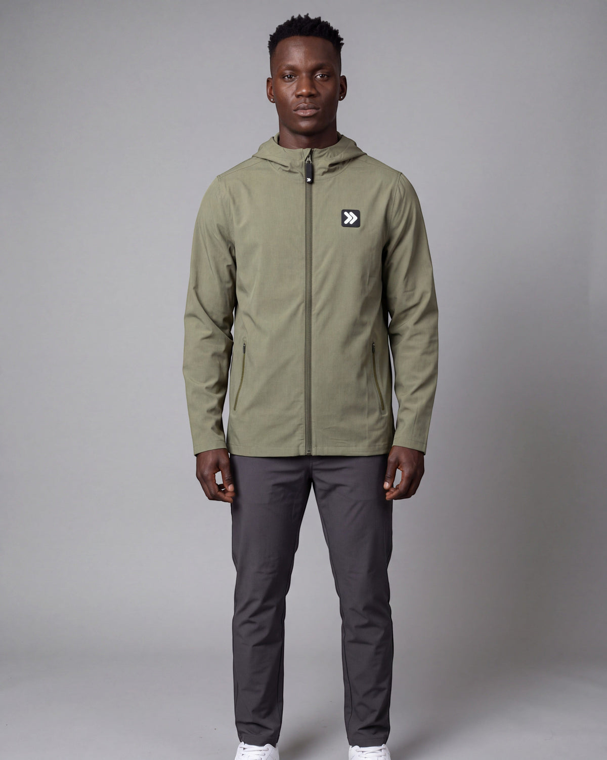 Male model wearing the MOVE Sport Apparel men’s Cactus hooded soft shell jacket with charcoal trousers in a neutral studio.