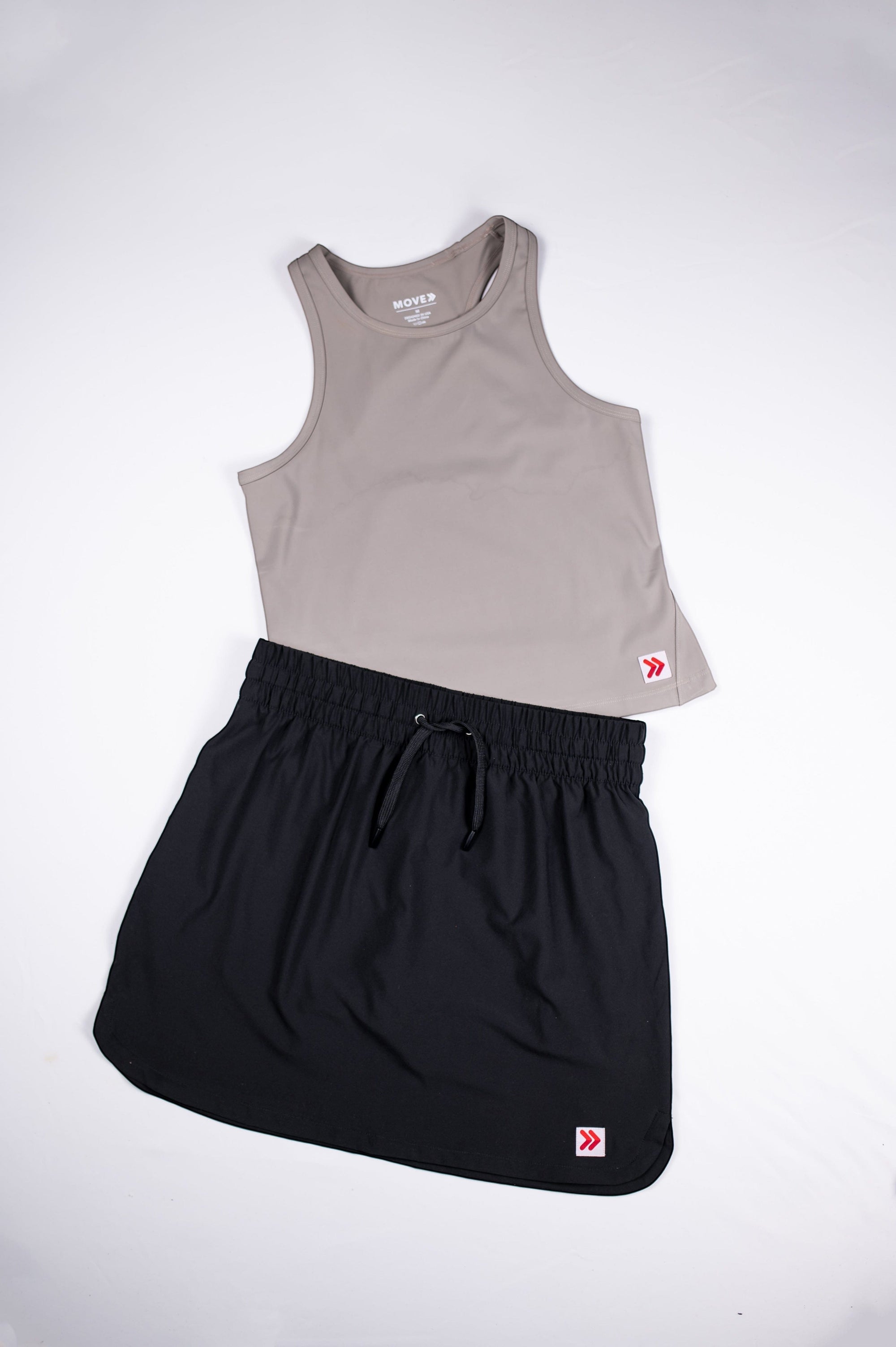 MOVE sport apparel women's taupe cropped tank top paired with a black athletic skort for fitness and workouts.