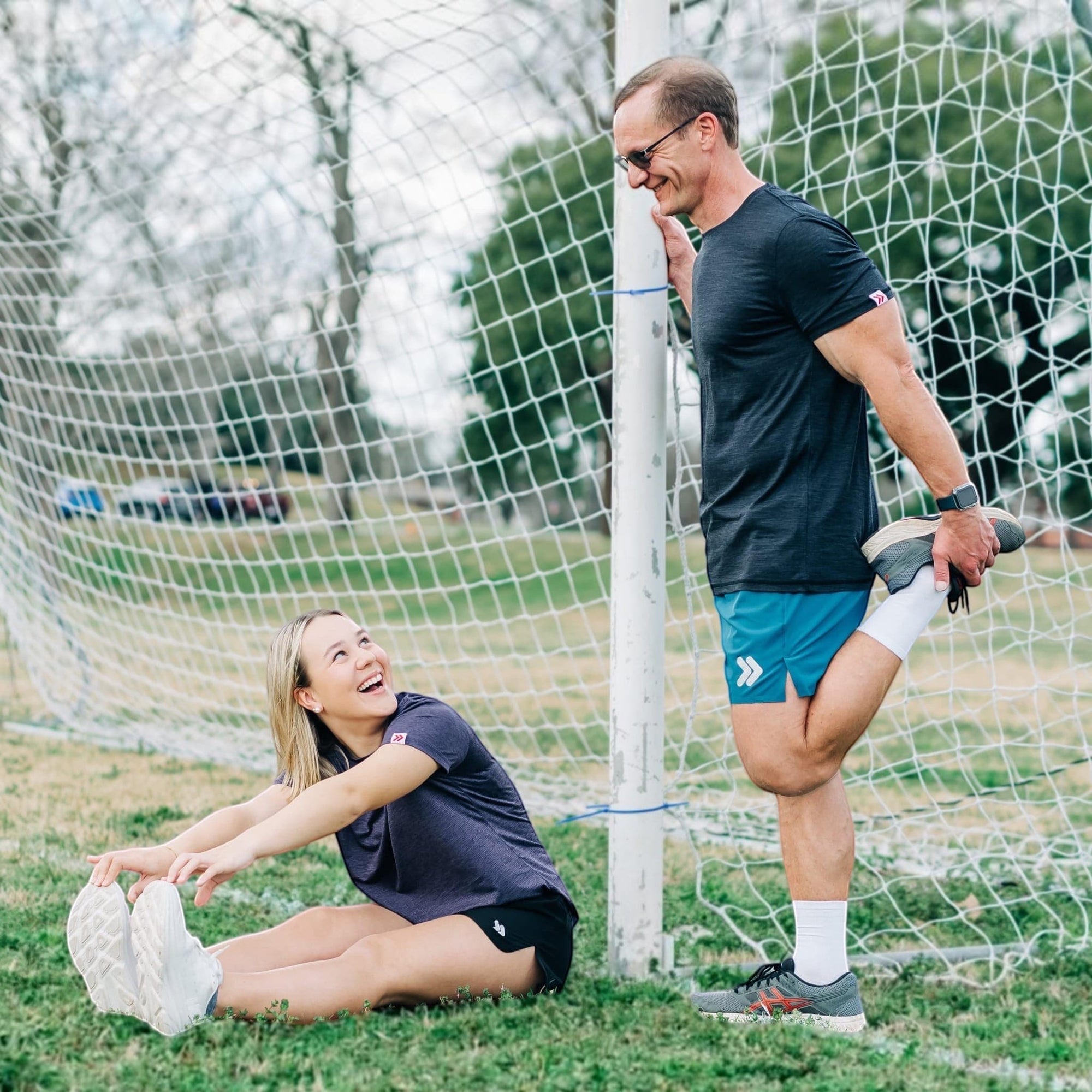 MOVE sport apparel Agility 6 inch training shorts in teal worn by a man stretching by a soccer goal outdoors