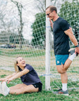 MOVE sport apparel Agility 6 inch training shorts in teal worn by a man stretching by a soccer goal outdoors
