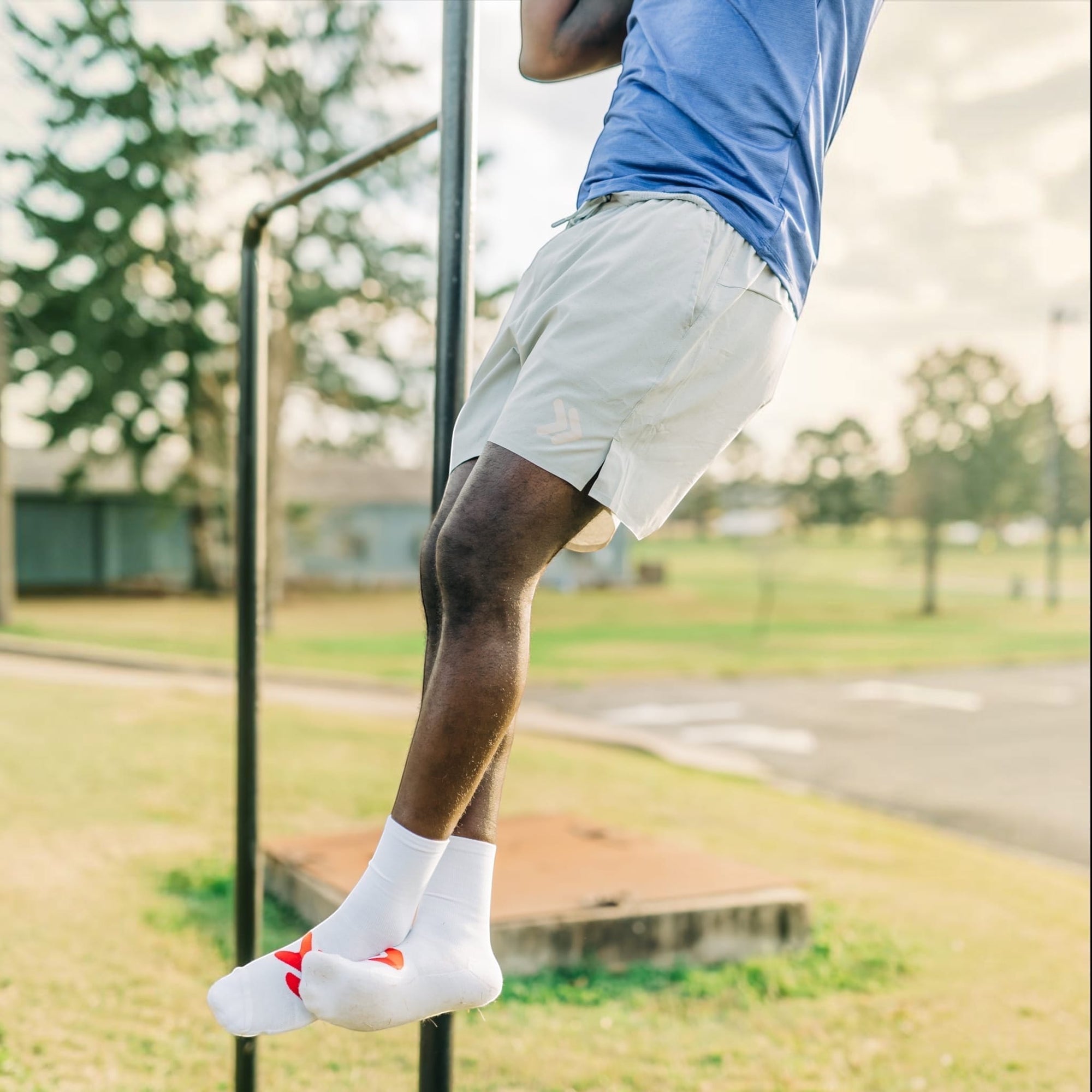 MOVE sport apparel Agility 6 inch training shorts in light grey worn by an athlete performing pull-ups outdoors