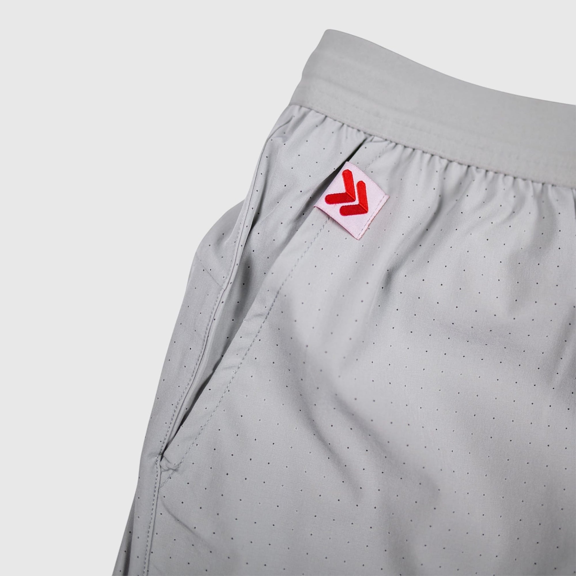 MOVE sport apparel Agility training shorts in light grey with perforated fabric and red logo tab on the pocket