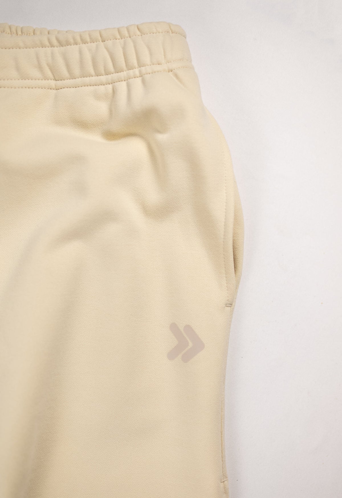 MOVE sport apparel beige French terry joggers featuring an elastic waistband and a subtle logo detail on the hip.