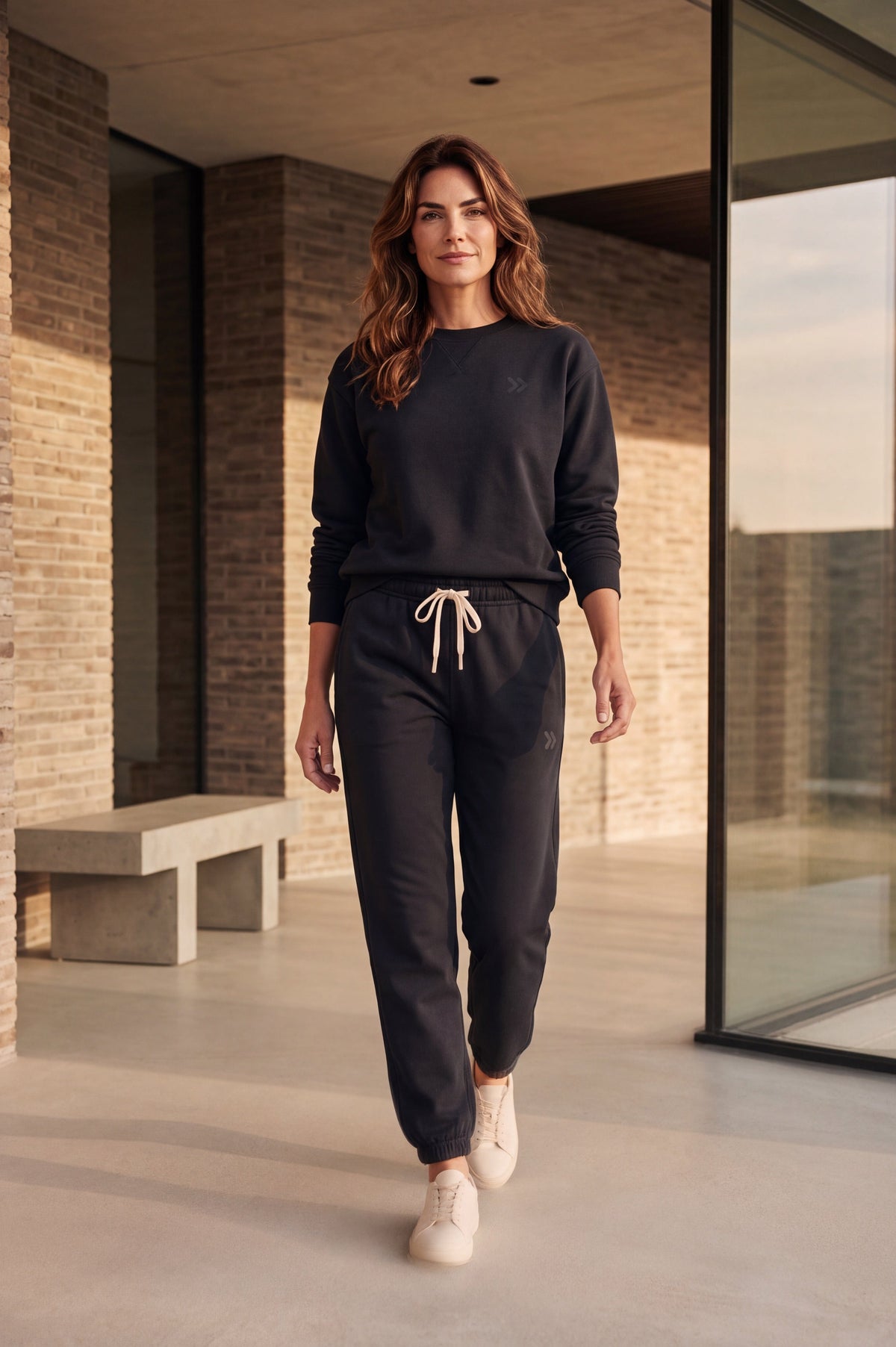 A woman wearing MOVE sport apparel black French terry joggers and matching sweatshirt with light-colored sneakers.